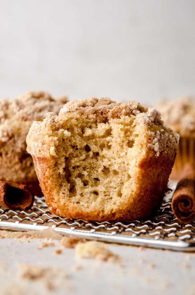 A coffee cake muffin with a bite taken out of it on a wire cooling rack.