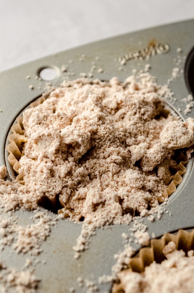 A closeup photo of a cinnamon streusel muffin in a baking pan before it's been baked.