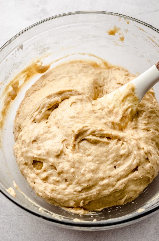 Cinnamon streusel coffee cake muffin batter in a bowl with a large spatula after resting for 15 minutes.