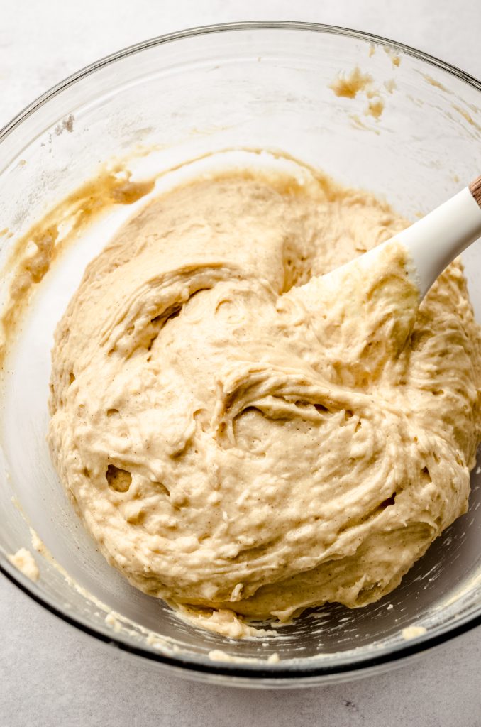 Cinnamon streusel coffee cake muffin batter in a bowl with a large spatula before the resting period.