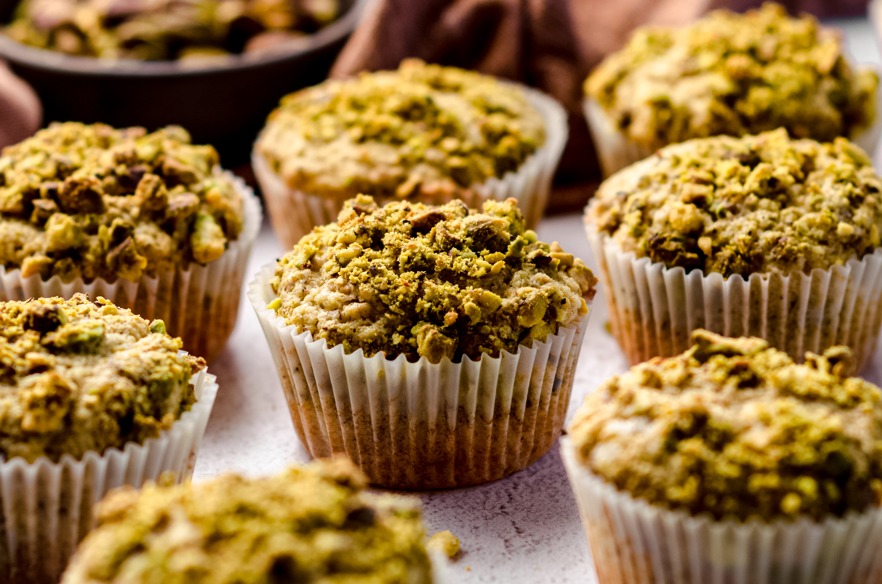Pistachio muffins on a surface.