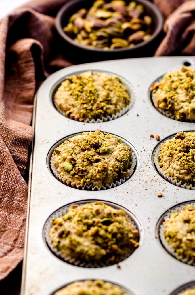 Baked pistachio muffins in a muffin tin.