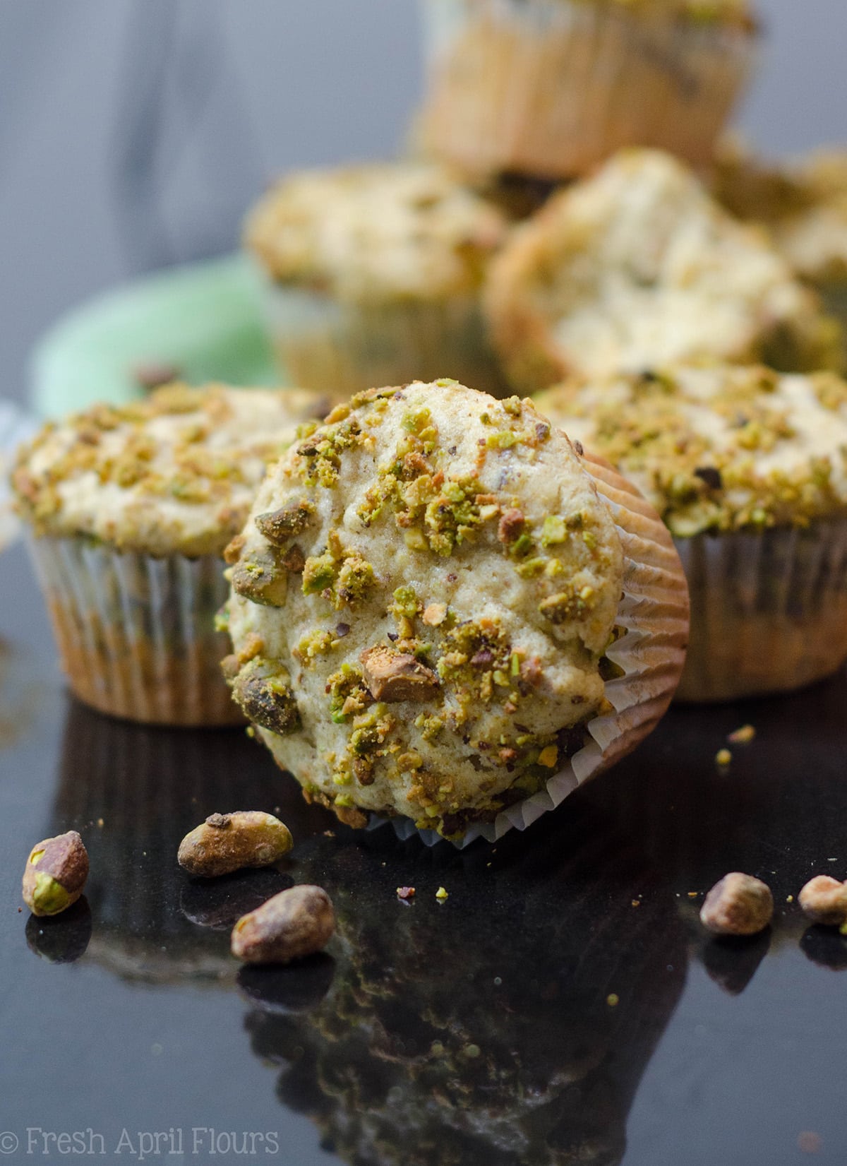 pistachio muffin on its side with muffins behind it