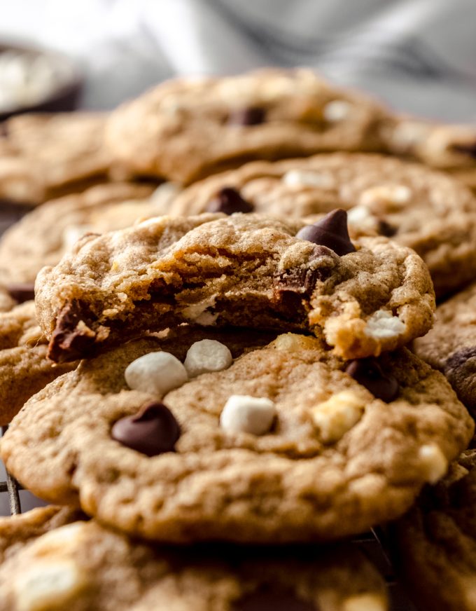 A stack of s'mores chocolate chip cookies with a bite taken out of the one on the top.