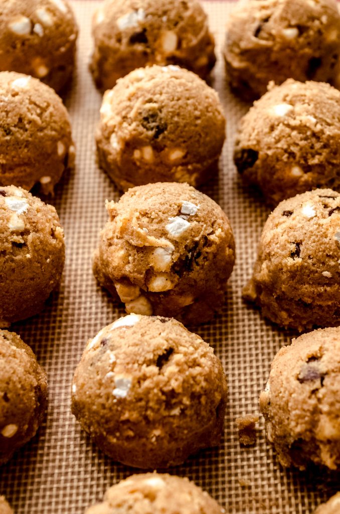 Balls of s'mores chocolate chip cookie dough on a baking mat.