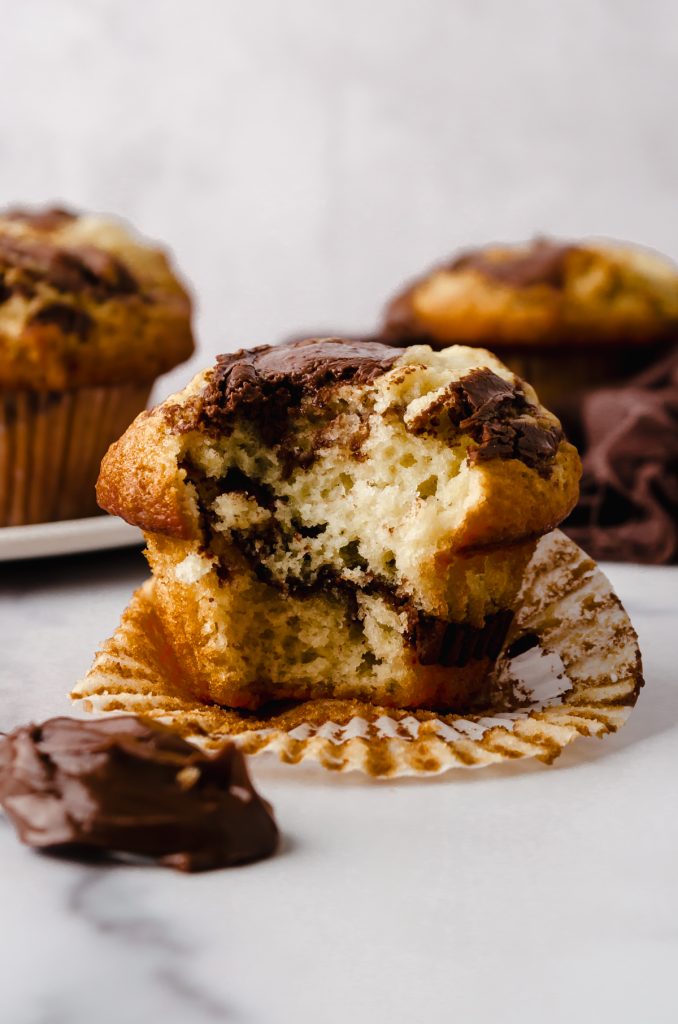 A Nutella muffin with a bite taken out of it on a surface.