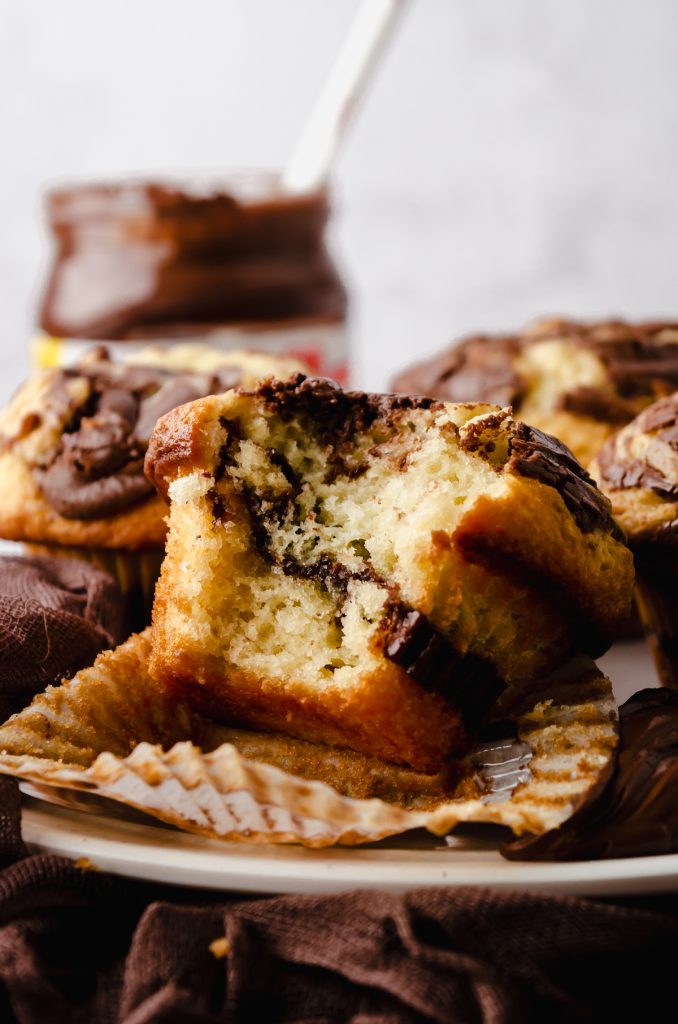A Nutella muffin with a bite taken out of it on a surface.