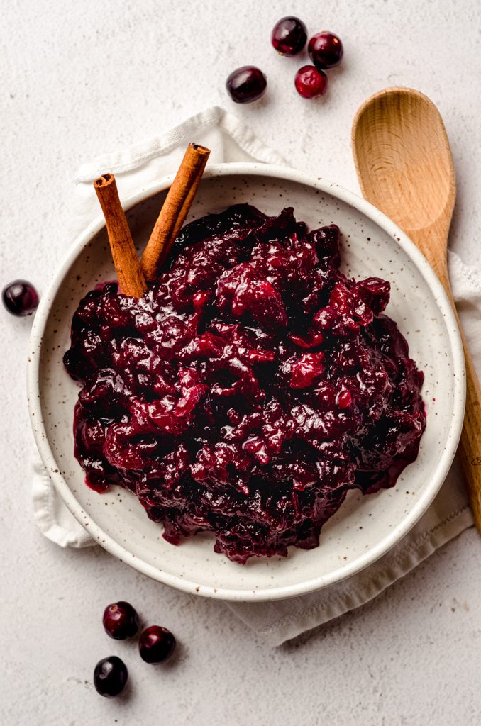 aerial photo of spiced cranberry sauce in a bowl with cinnamon sticks