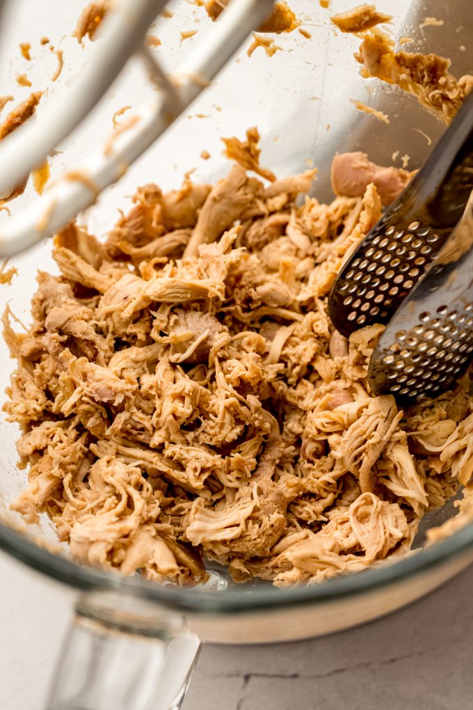 Shredded hot chicken in the bowl of a stand mixer.