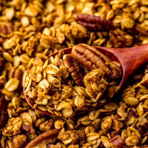 Pumpkin granola with a wooden spoon in it.