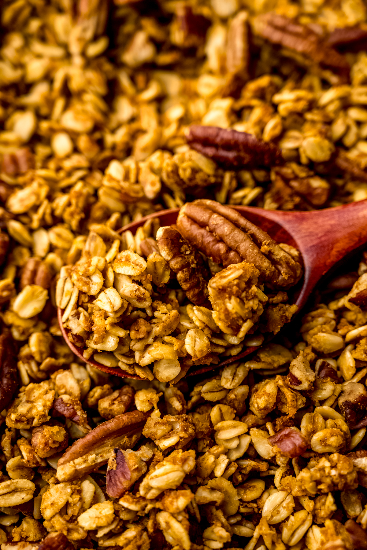 Pumpkin granola with a wooden spoon in it.