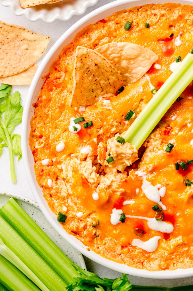 Aerial photo of buffalo chicken dip in a dish with a stick of celery.