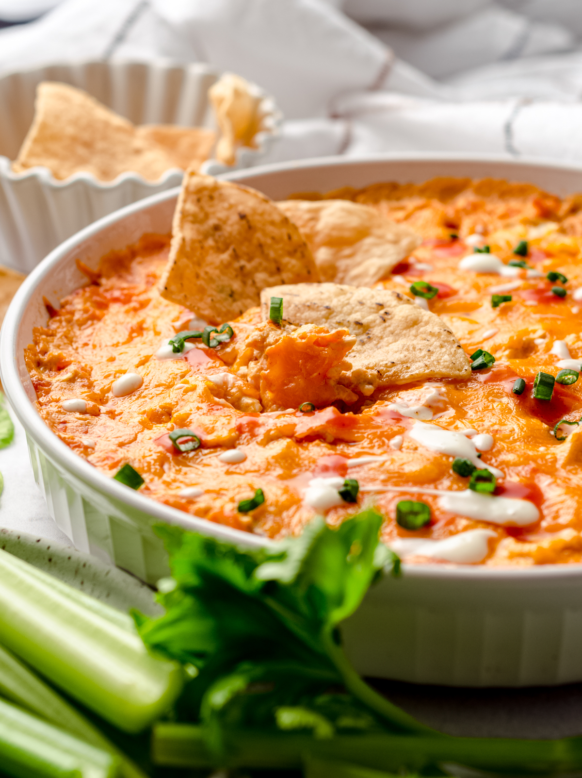 A dish of buffalo chicken dip with chips in it.