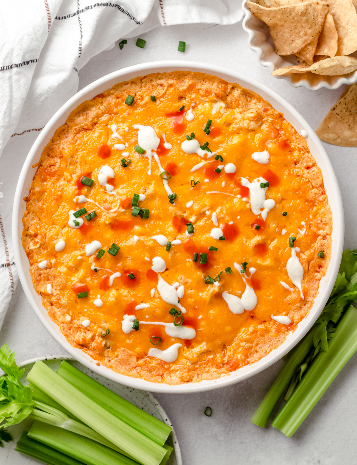 An aerial photo of buffalo chicken dip in a dish with chips and celery around it.