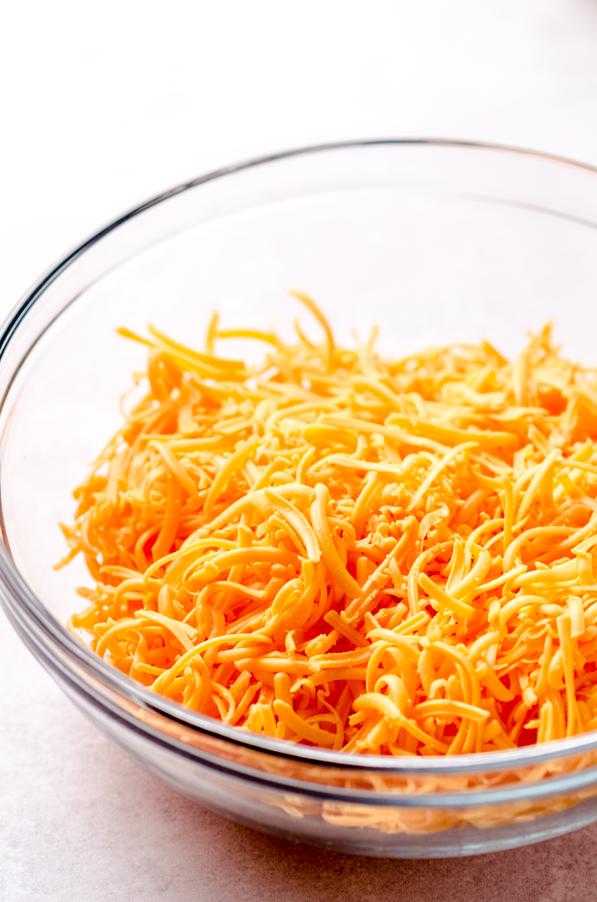 A bowl of freshly shredded cheddar cheese.