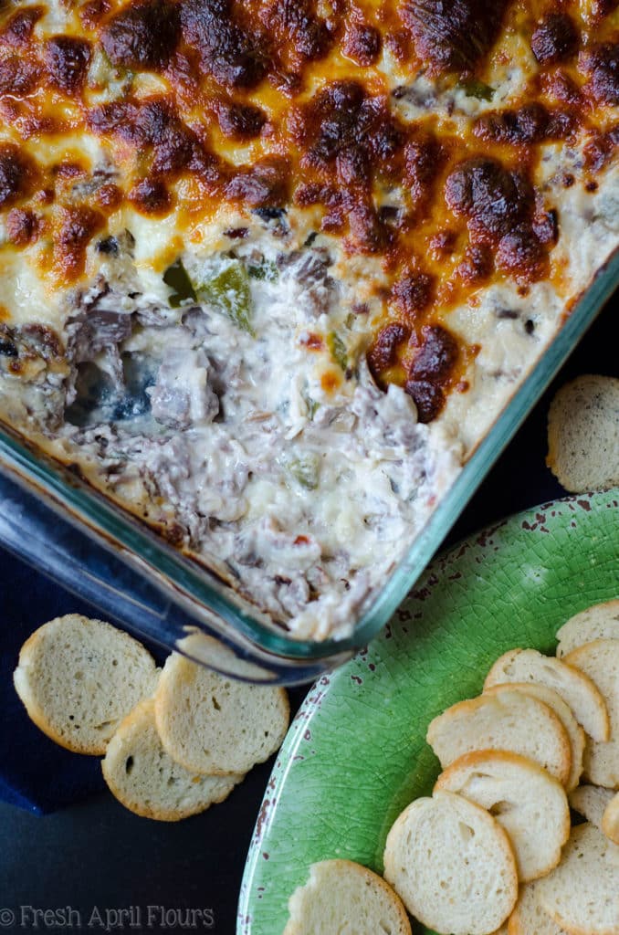 Philly Cheesesteak Dip: Creamy dip filled with flavorful onions, green pepper, mushrooms, and roast beef, topped with a crispy layer of provolone cheese.