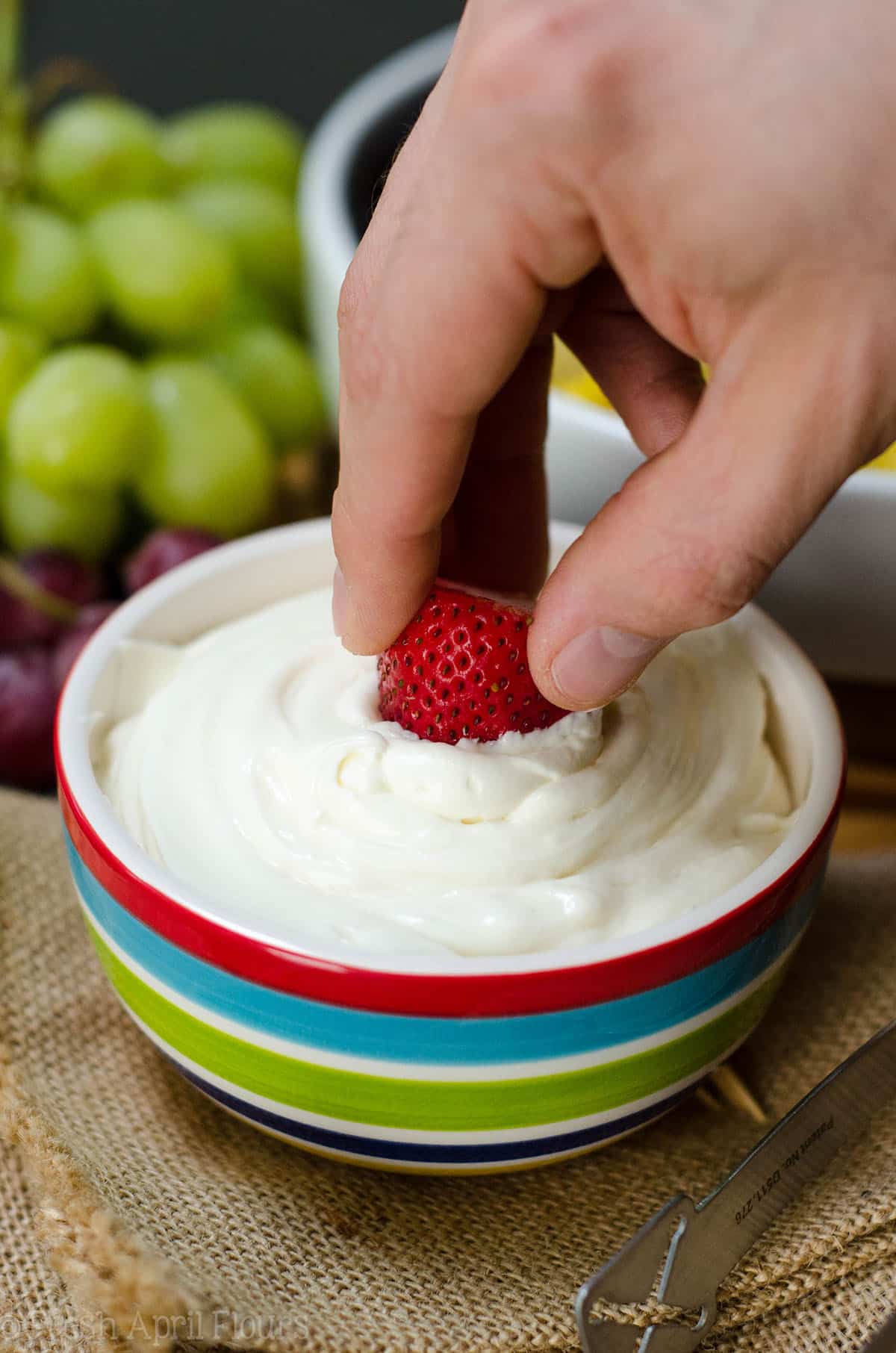 hand dipping a strawberry into fruit dip