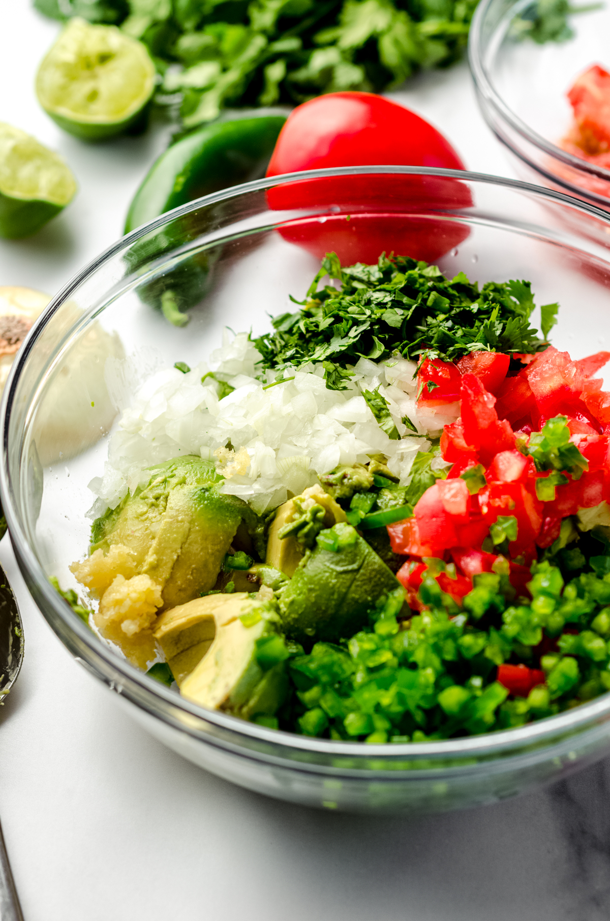 A large glass bowl full of ingredients to make homemade guacamole.