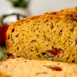 Sliced tomato basil bread on a surface.