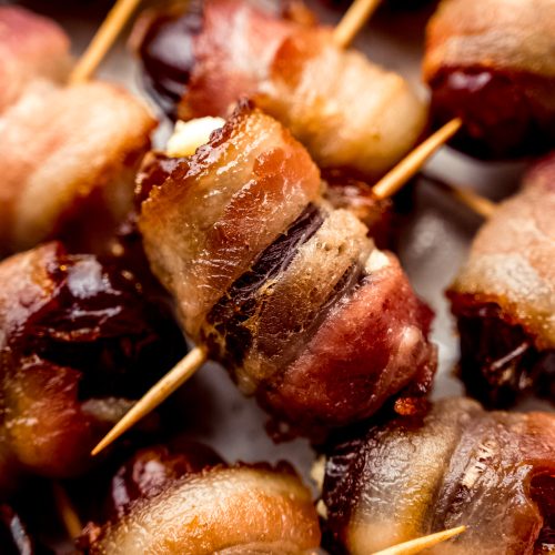 A closeup photo of a bacon wrapped date stuffed with goat cheese.