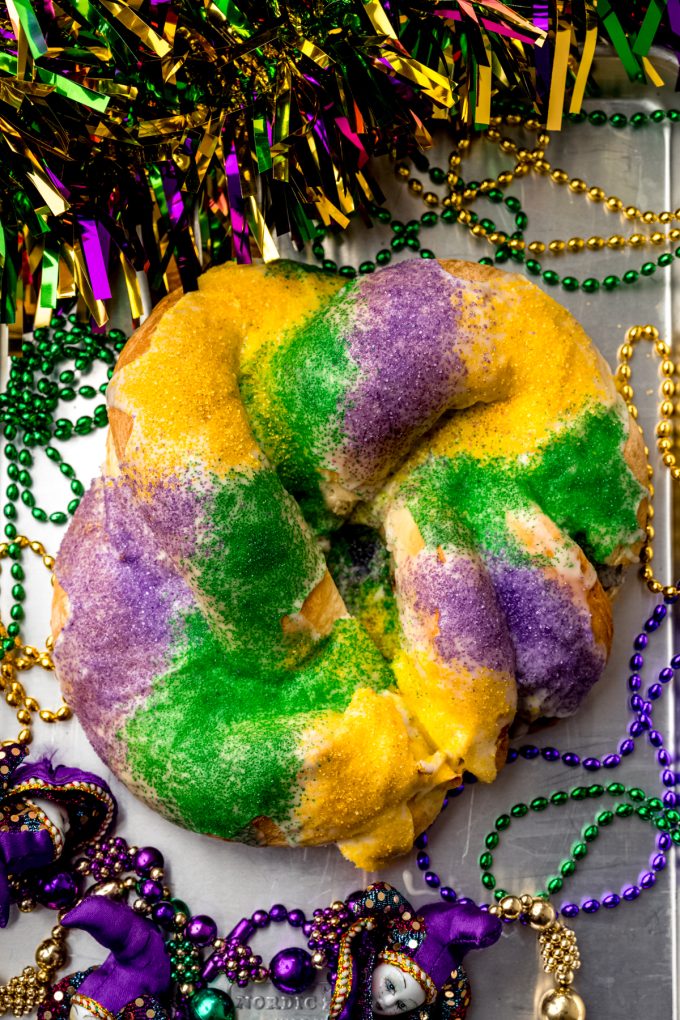 Aerial photo of a Mardi Gras king cake on a surface.