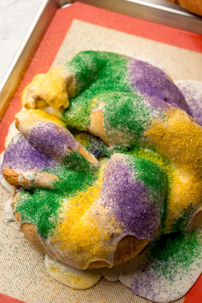 A Mardi Gras king cake on a baking sheet after it has been decorated.