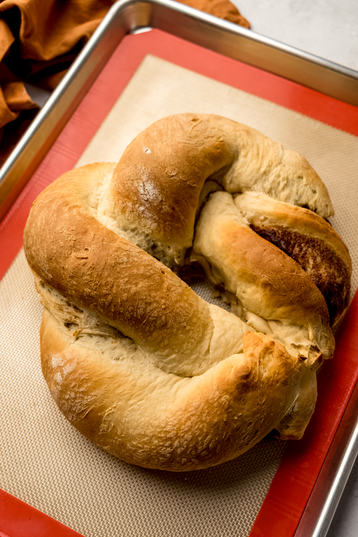A baked Mardi Gras king cake on a baking sheet before it gets decorated.