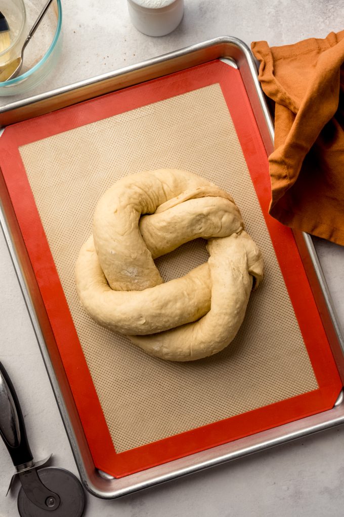 Shaped but not yet risen Mardi Gras king cake on a baking sheet.