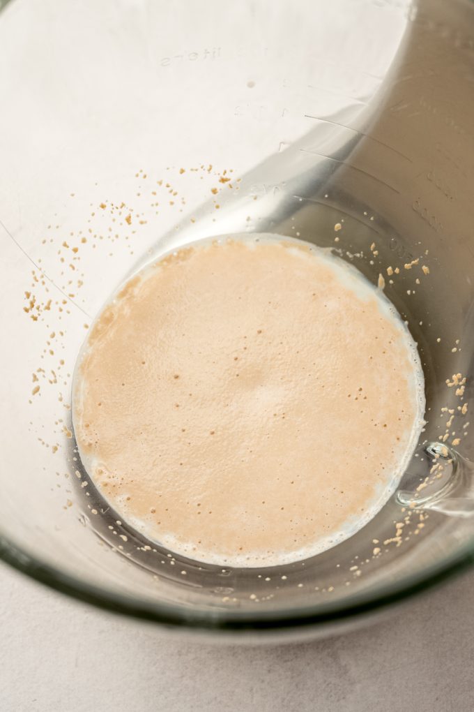 A mixture of yeast and milk in the bottom of a mixing bowl.