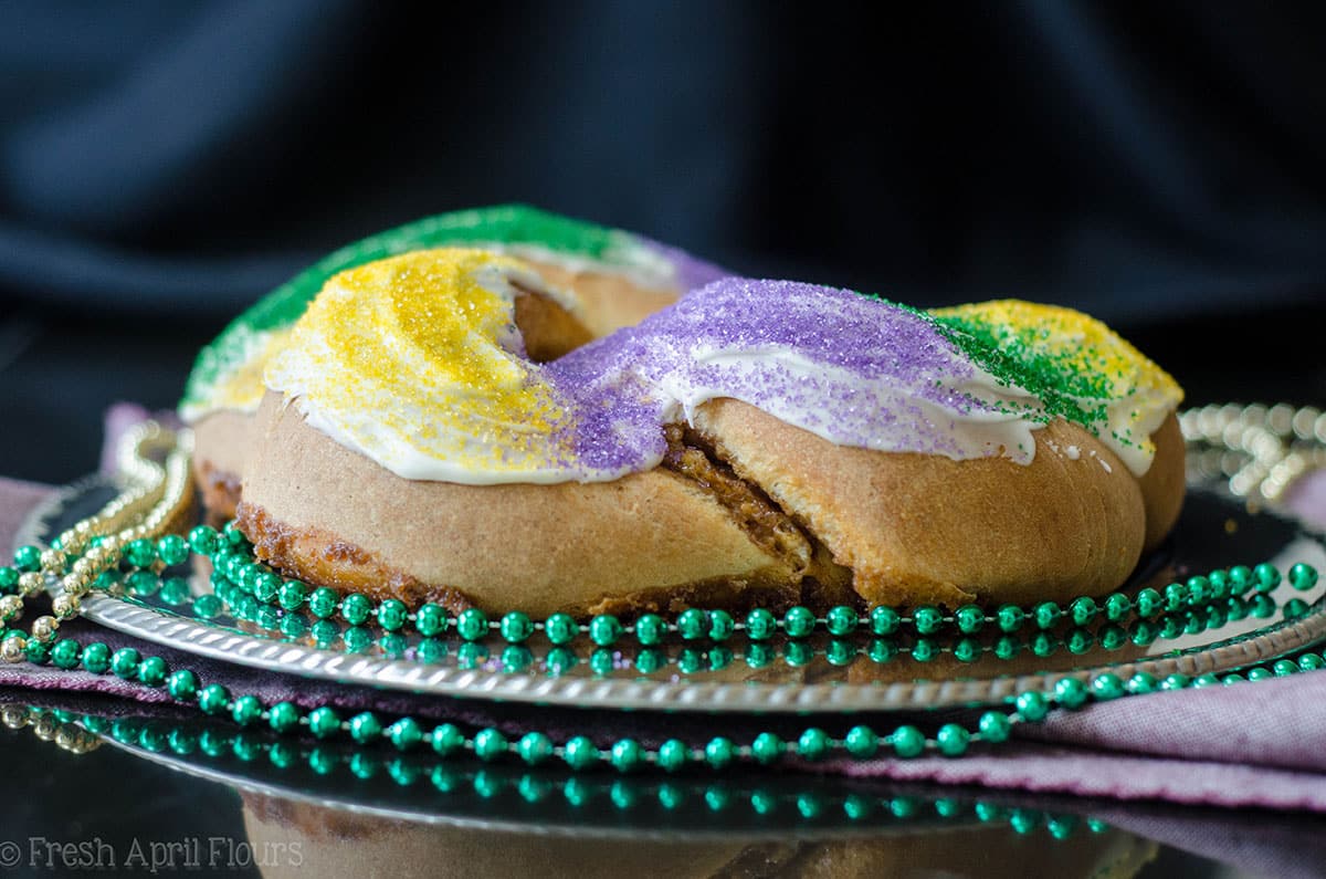 mardi gras king cake on a platter surrounded by beads