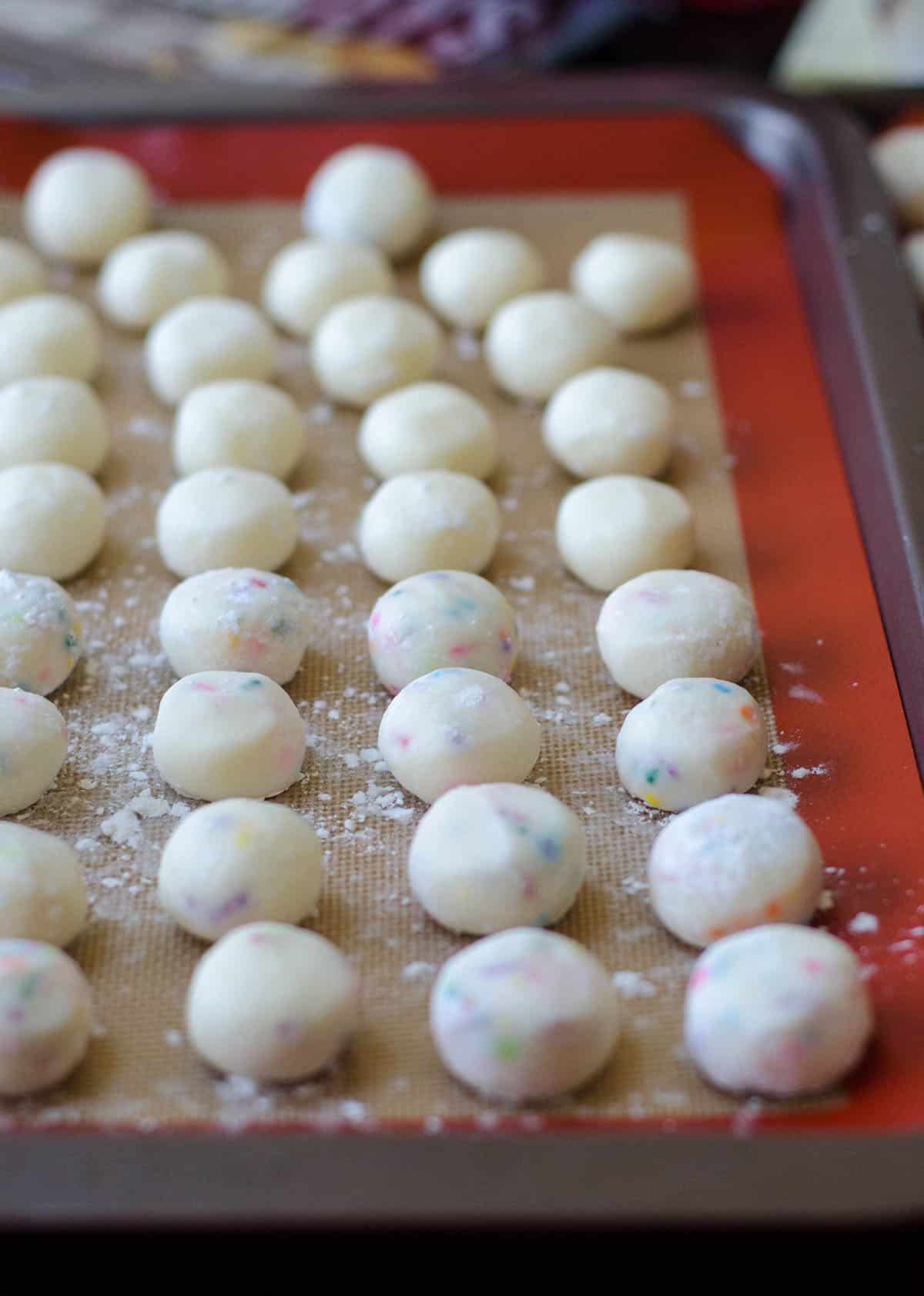 funfetti buttercreams on a baking sheet ready to dip in chocolate
