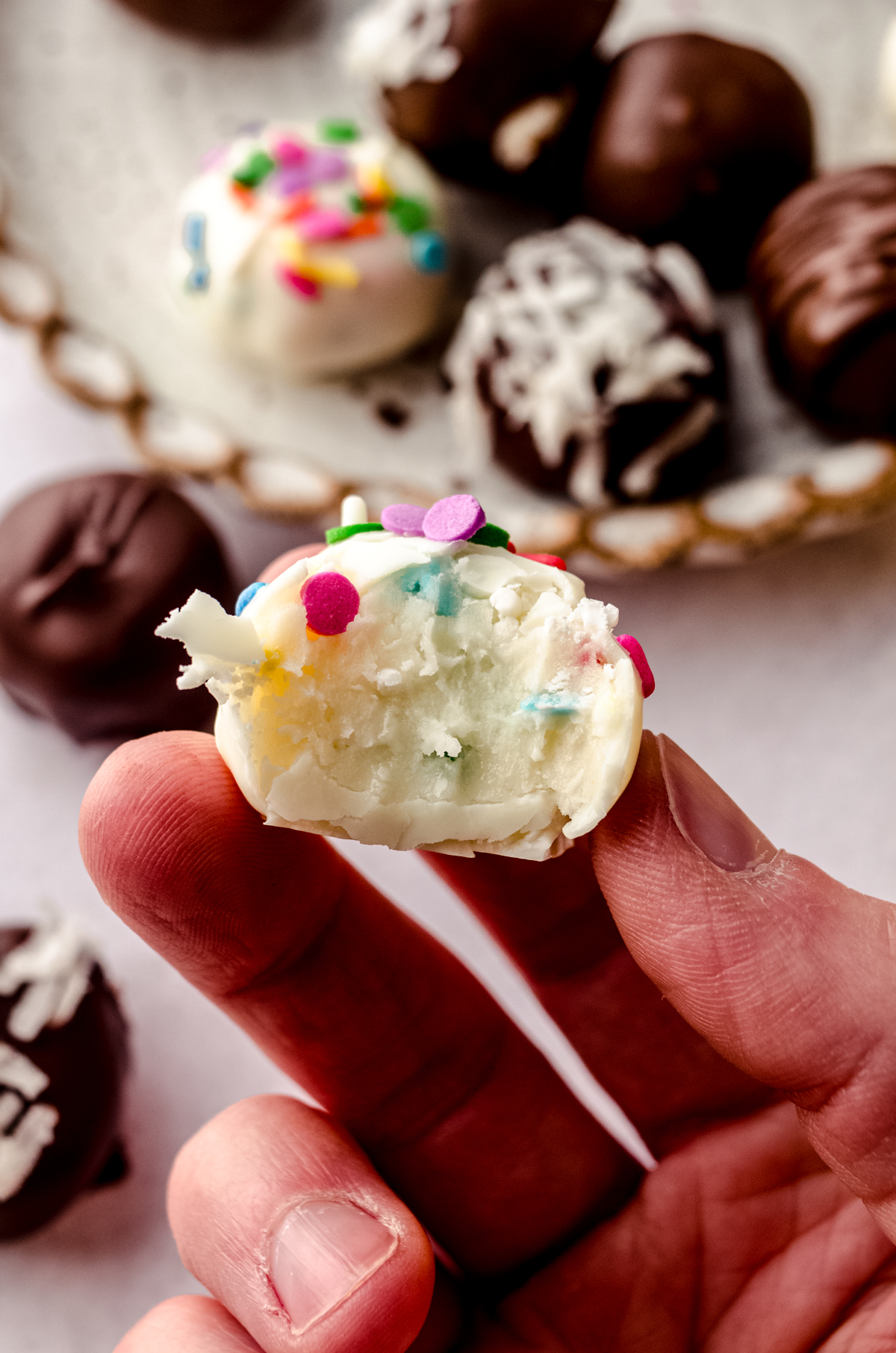 Someone is holding a funfetti buttercream Easter candy with a bite taken out of it.