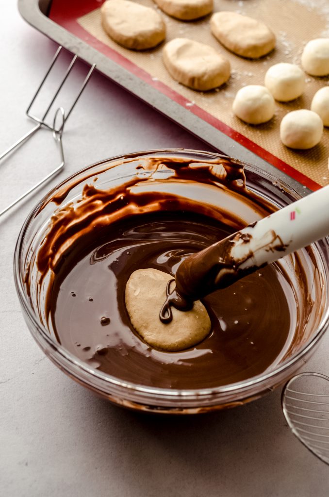 Someone is dipping a peanut butter egg into chocolate coating to make Easter candy.