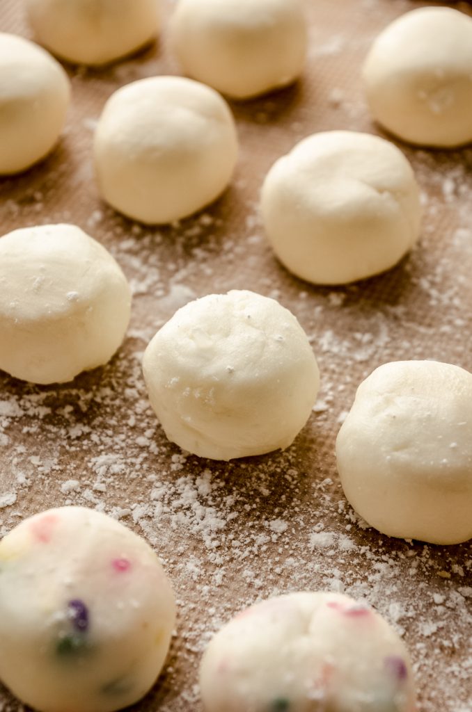 Coconut buttercream rounds filling on a baking sheet before getting dipped in chocolate.