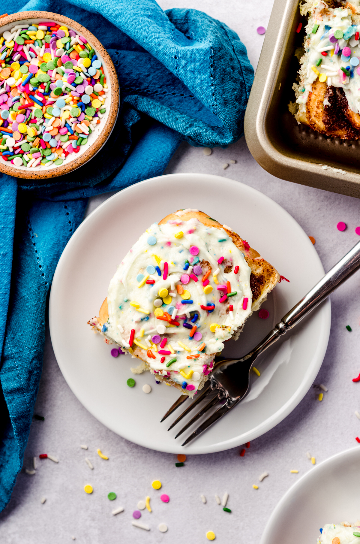 Aerial photo of a funfetti cinnamon roll on a plate with a fork.
