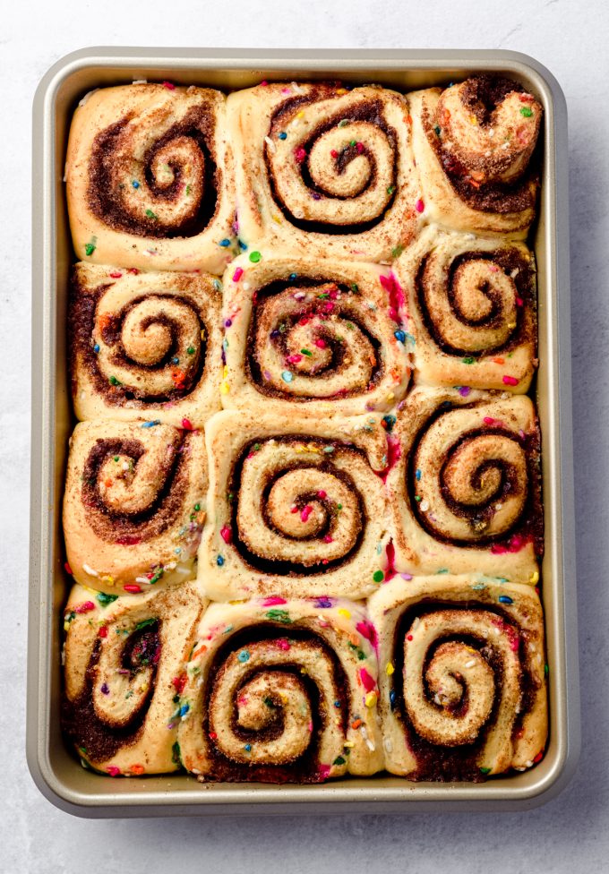 Aerial photo of baked funfetti cinnamon rolls in a baking pan.