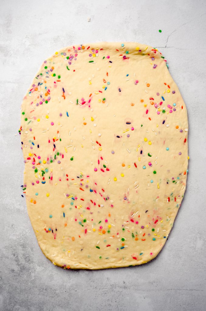 Aerial photo of funfetti cinnamon roll dough rolled out into a rectangle.
