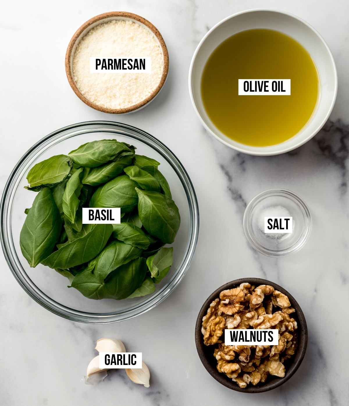 Aerial photo of ingredients to make homemade pesto with text overlay labeling each ingredient.