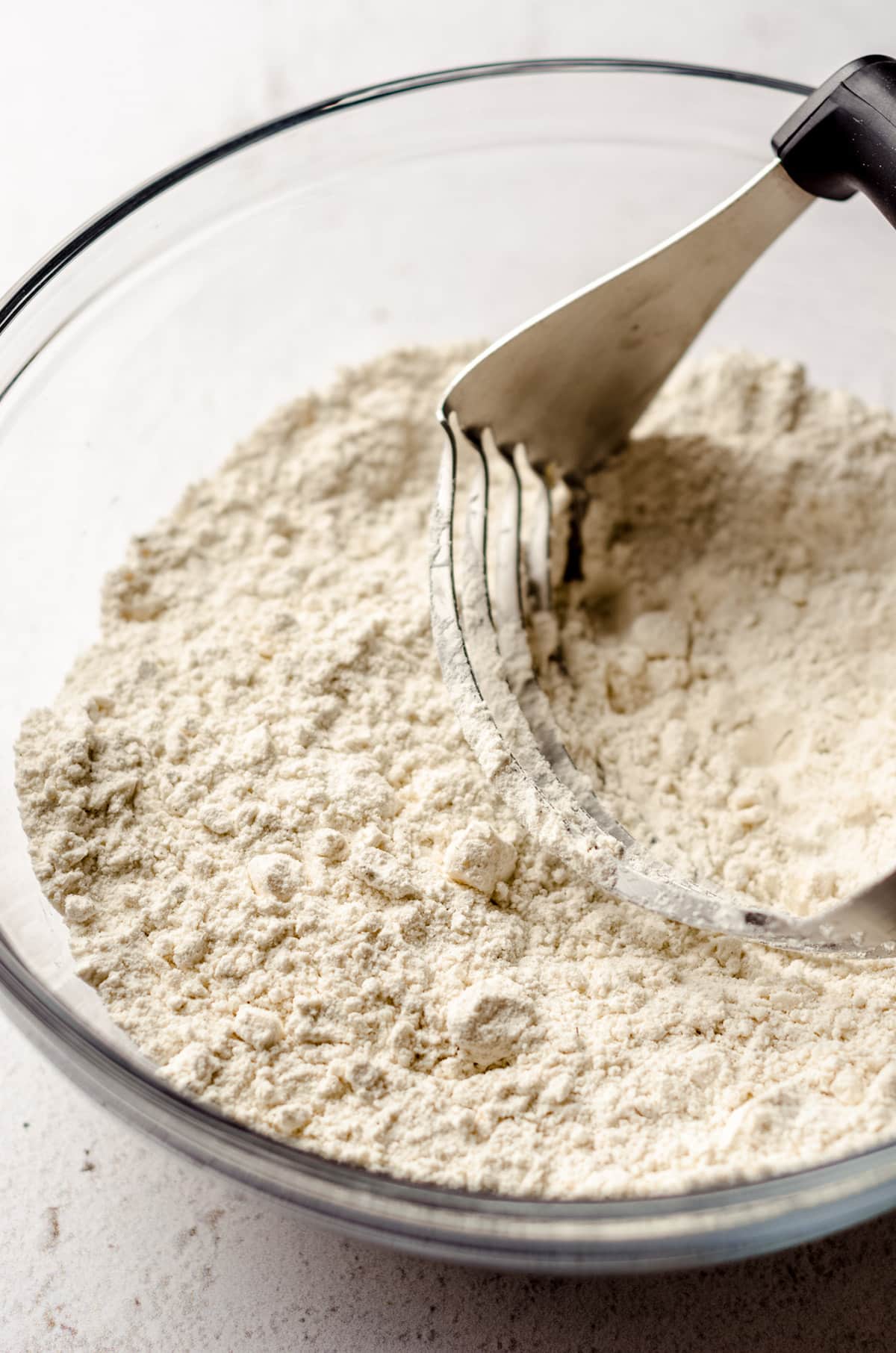 pastry cutter cutting butter into flour for biscuits