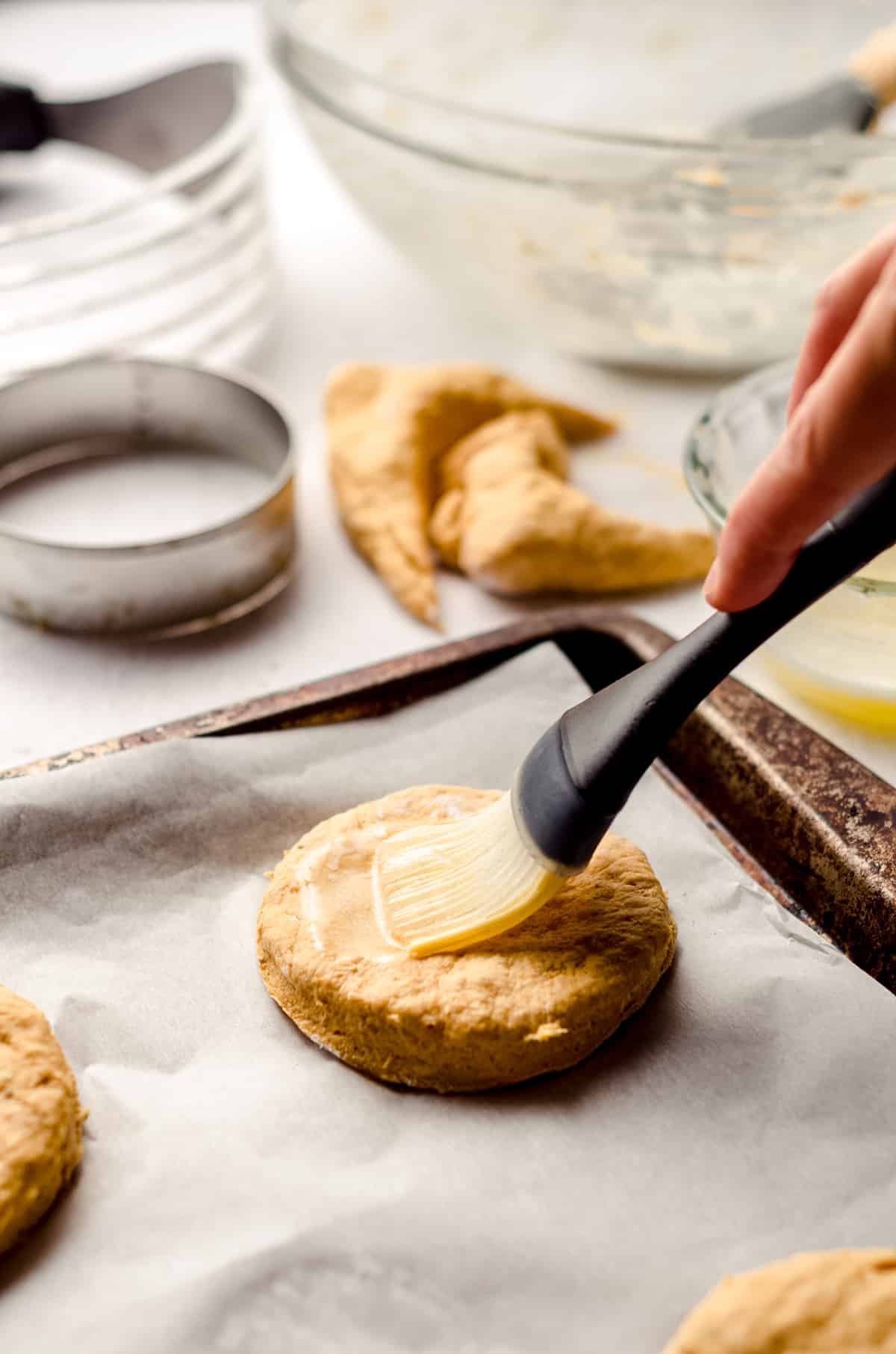 brushing savory pumpkin biscuit cut-outs with butter