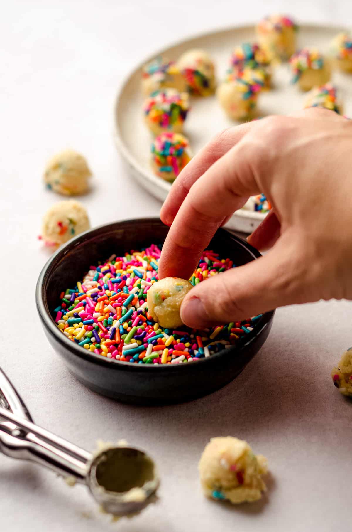 dipping a ball of cookie dough into sprinkles