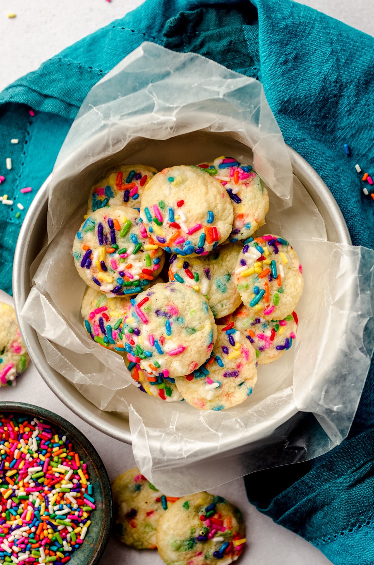 aerial photo of mini drop sugar cookies with sprinkles in a cookie tin