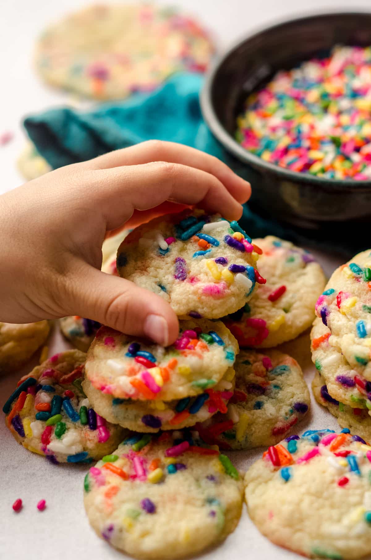 child's hand grabbing mini sugar cookies with sprinkles