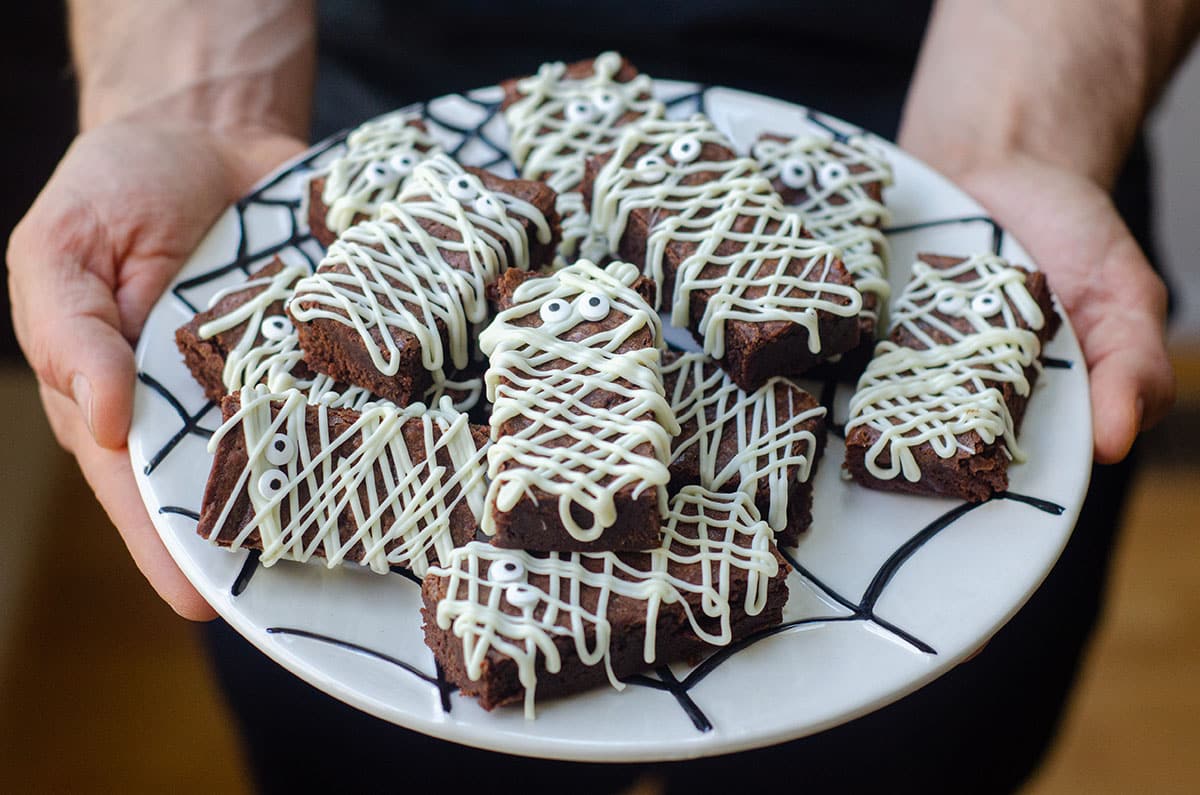 hands holding a plate of mummy brownies