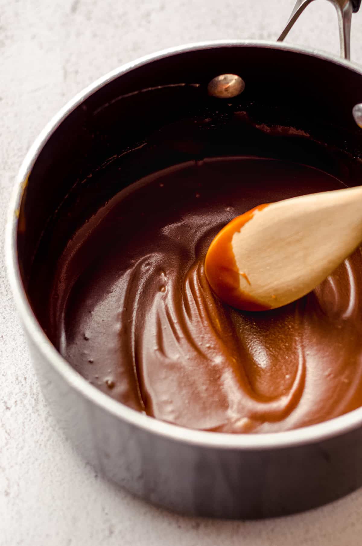 wooden spoon stirring bourbon salted caramel sauce in a saucepan