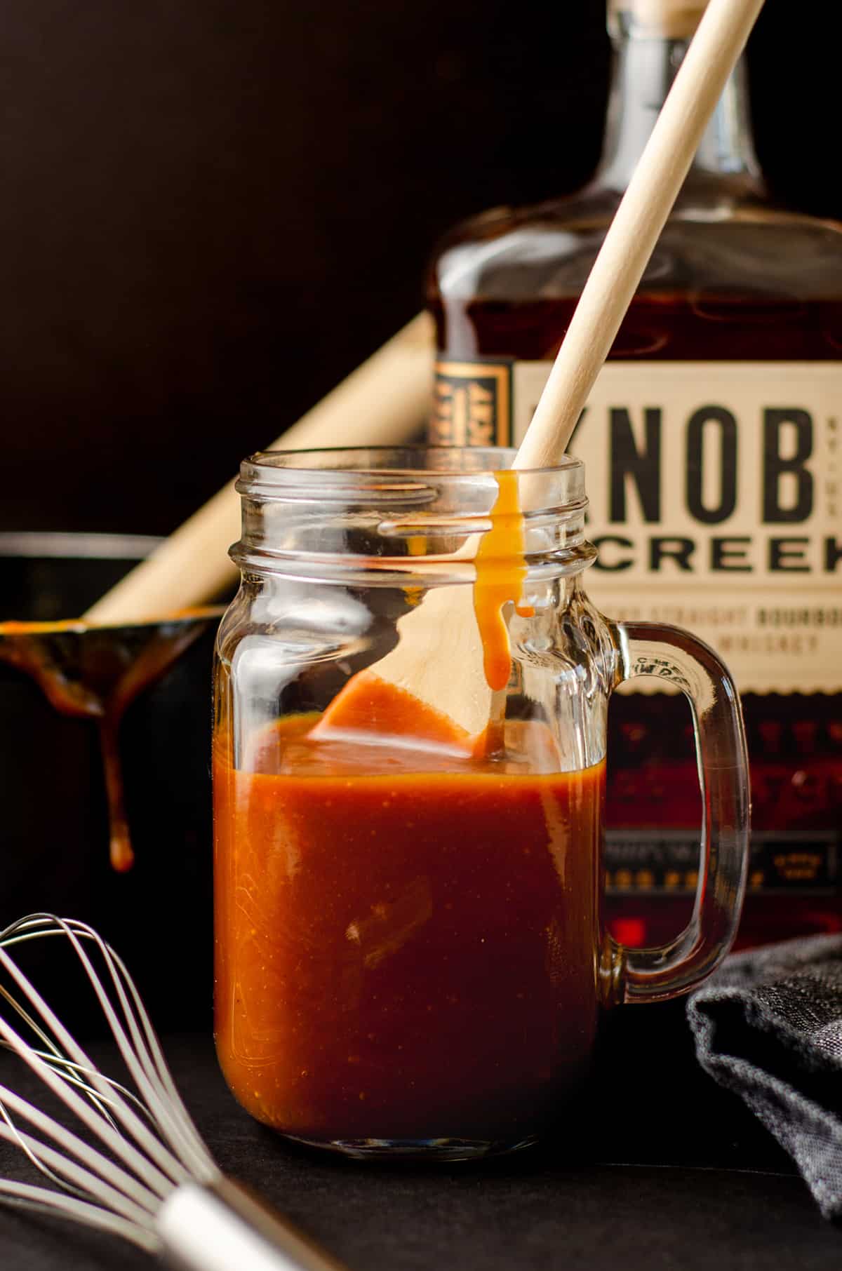 a wooden spoon in a glass jar of salted bourbon caramel sauce