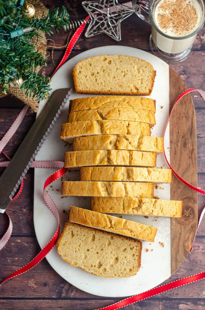 aerial photo of sliced eggnog bread with knife, ribbon, and glass of eggnog