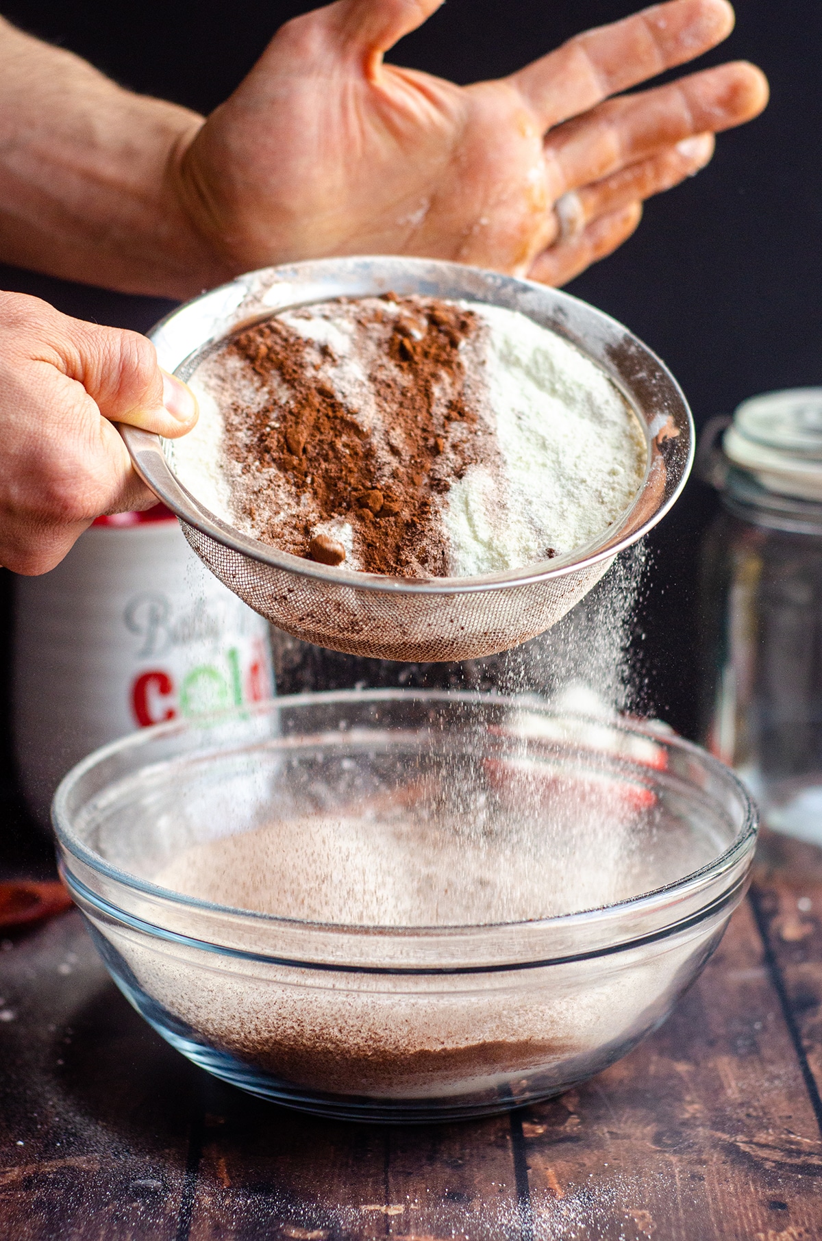 sifting powdered sugar and cocoa powder into a bowl for homemade hot cocoa mix