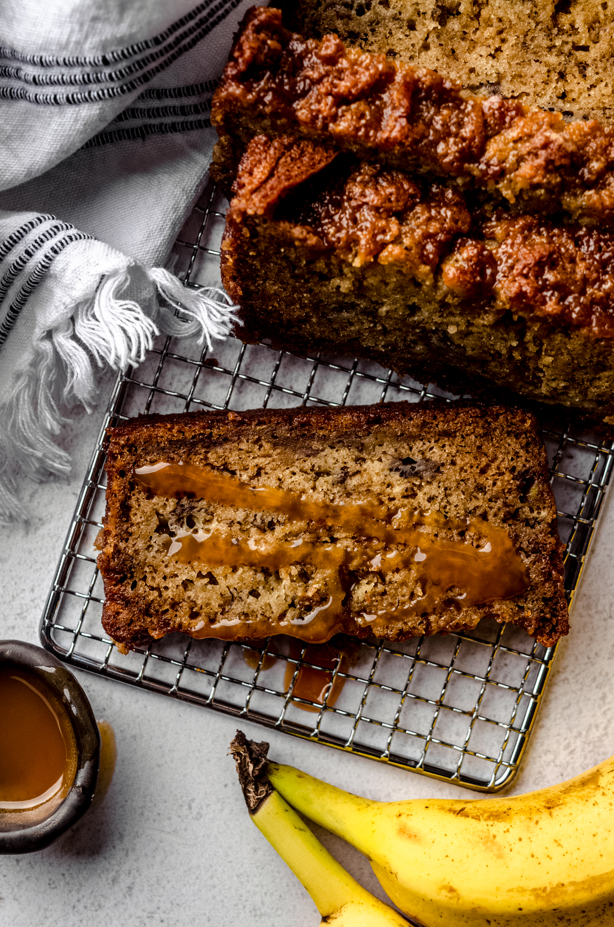 Aerial photo of a slice of salted caramel banana bread on a cooling rack.