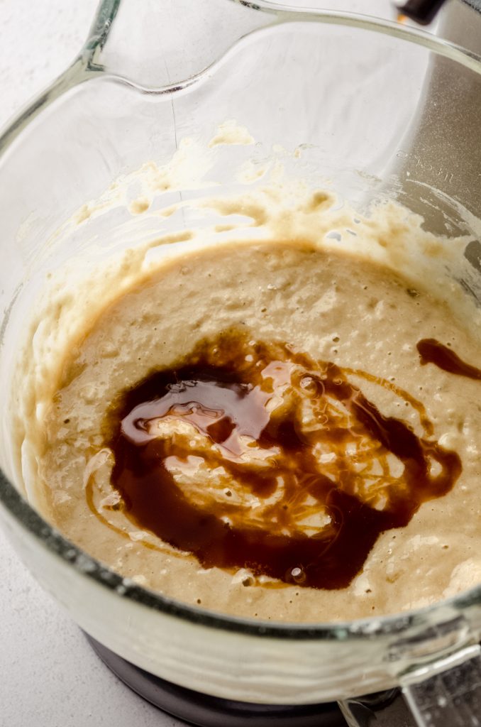 Salted caramel sauce swirled into banana bread batter in a bowl.